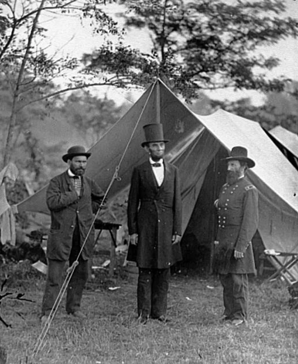 Black-and-white 1862 glass-plate scan of three men at a military tent